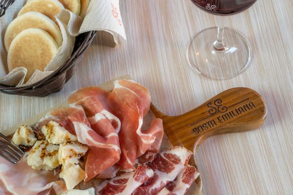 Tagliere di salumi con tigelle e gnocco, e un calice di lambrusco